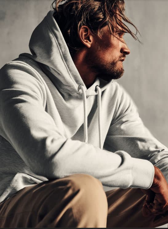 Model sitzt mit grauem hoodie in dei Ferne blickend