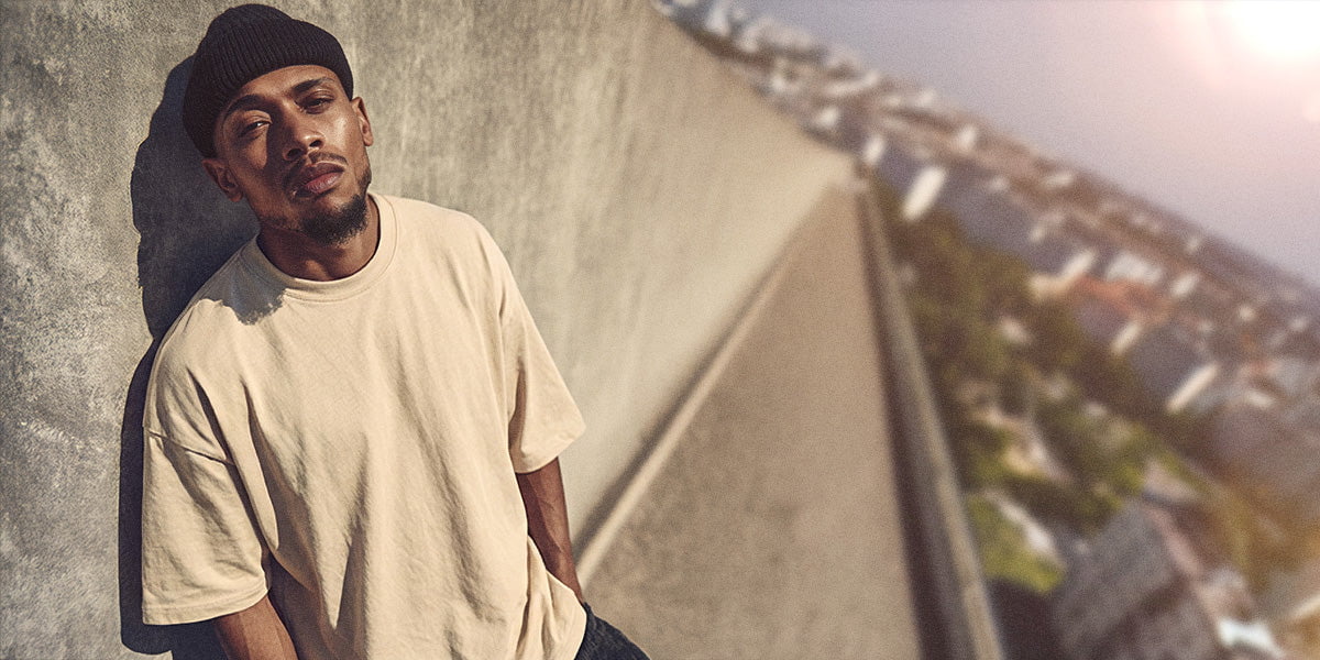 Model in gelblichem oversize hoodie an die Fassade gelehnt