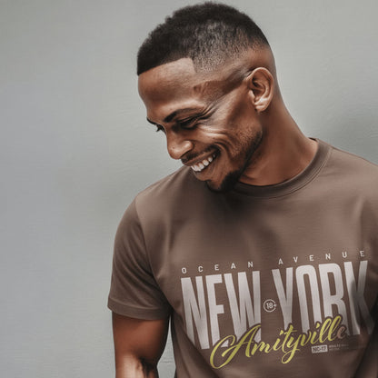 Organic T-Shirt 'AMITYVILLE NY' – Mann von vorne, taupe T-Shirt mit cinematischem Frontprint 'New York Amityville'. Premium Cinematic Streetwear. Film Art Wear – Designed in Hamburg.