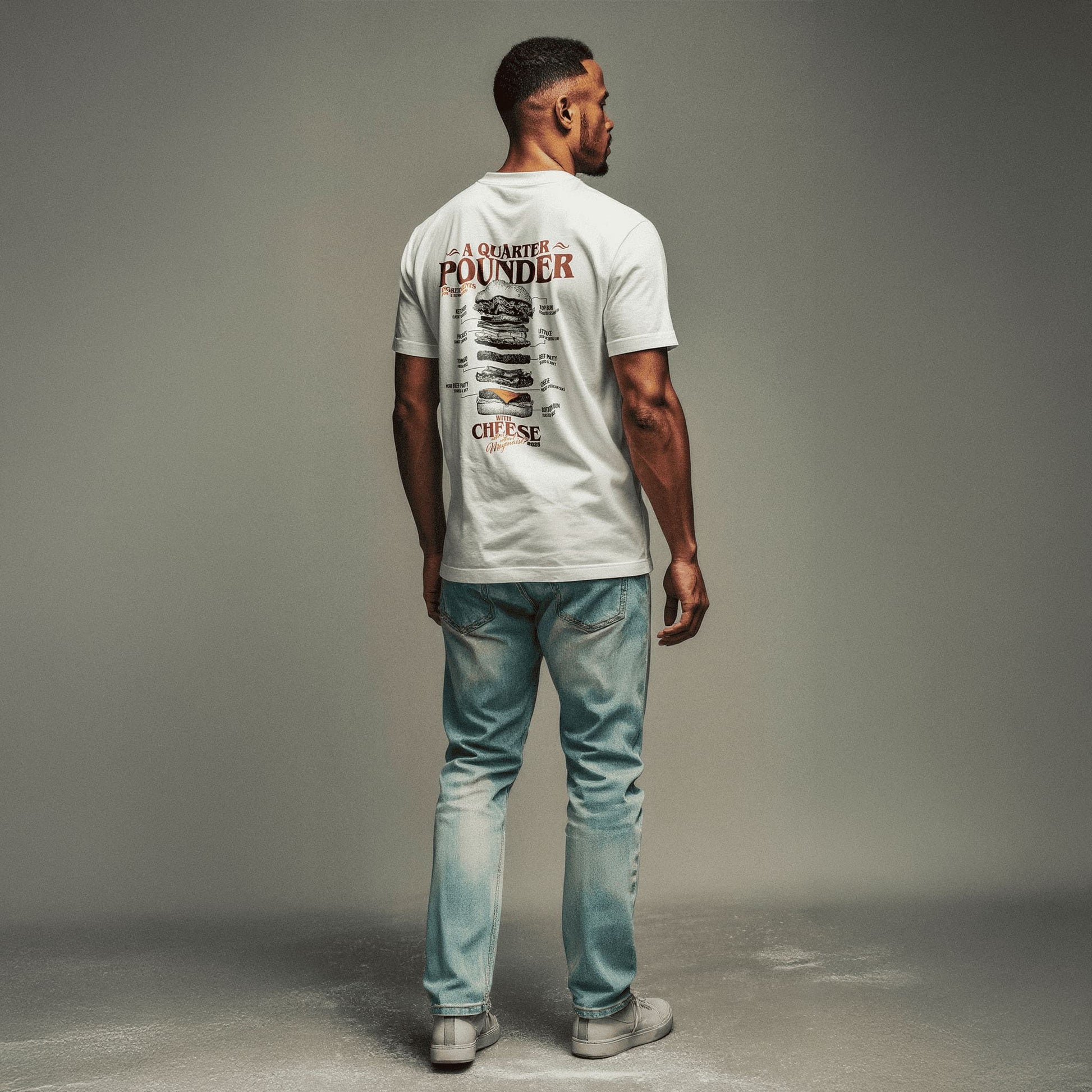 Männliches Models mit Jeans, Sneakern und weißem T-Shirt mit großem Backprint "Quarterpounder with cheese" und der grafischen Zutatenliste