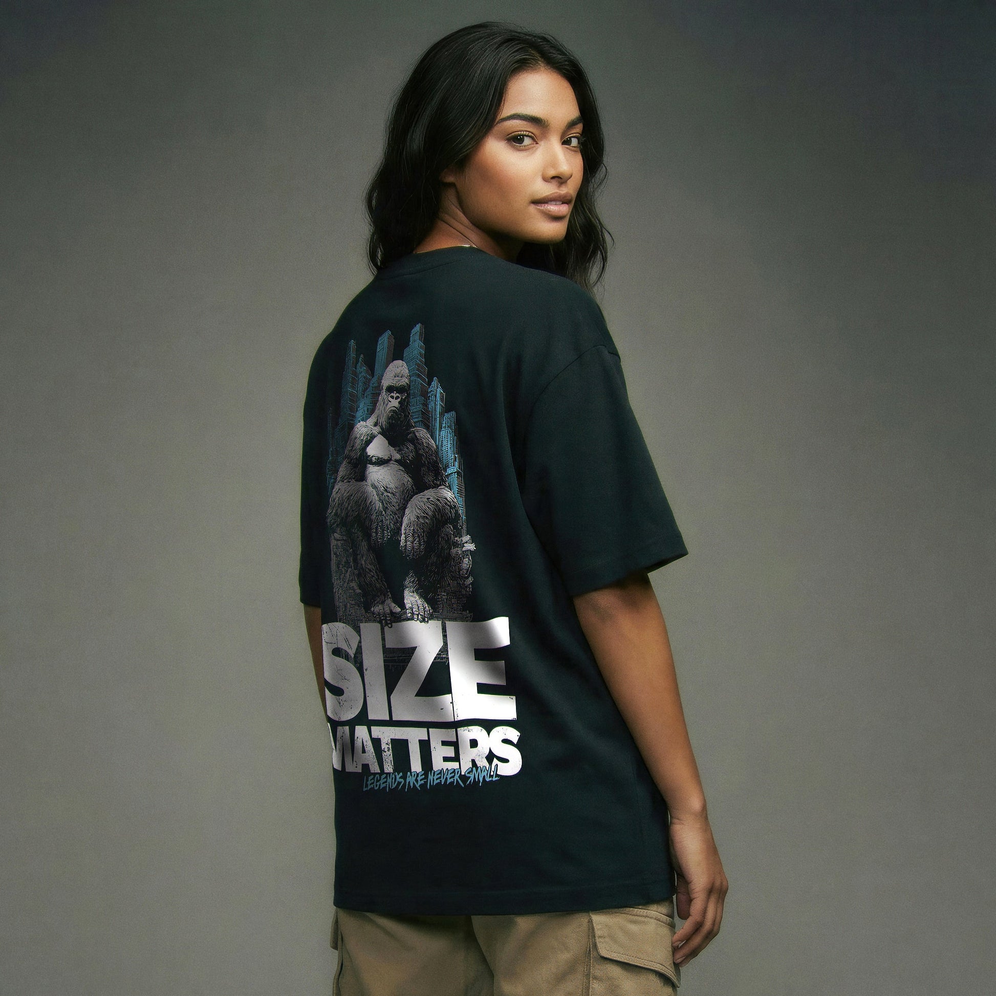 Organic T-Shirt 'SIZE MATTERS' – Frau von hinten, schwarzes Oversize T-Shirt mit großflächigem Backprint 'Size Matters'. Heavy Oversize Fit. Premium Cinematic Streetwear. Film Art Wear – Designed in Hamburg.